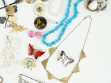 many different necklaces and earrings on a white surface