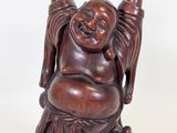 an image of a statue of a laughing buddha sitting on a tree stump