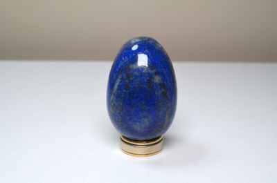 un œuf bleu posé sur une table blanche