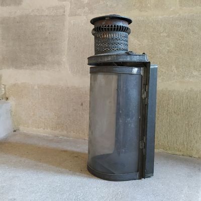 une lanterne noire posée par terre près d'un mur