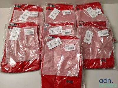 six paires de pantalons rouges sont emballées dans des sacs en plastique sur une table