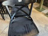 Plusieurs chaises noires sont empilées les unes sur les autres dans une pièce