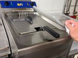 un homme debout dans une cuisine, devant une friteuse