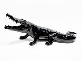 un alligator noir posé sur une surface blanche