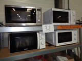 trois micro-ondes posés sur une étagère dans un magasin