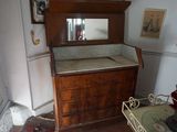 une commode dans un coin de la pièce, avec des tableaux accrochés au mur