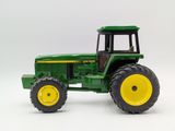 a green toy tractor with yellow wheels on a white background