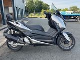 une moto argentée et noire garée devant un immeuble