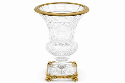 une image représentant un vase en verre à bord doré posé sur un socle