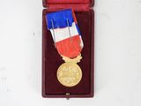 a gold medal with a red, white, and blue ribbon in a red case