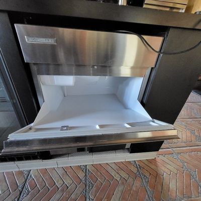 un four en acier inoxydable dont la porte s'ouvre sur un sol en briques