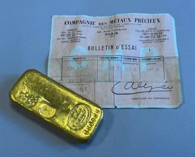 un lingot d'or à côté d'un ticket de caisse, posé sur une surface bleue