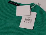 the shirt is green and has a white tag on it