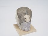 une petite sculpture représentant un homme barbu, posée sur un socle en bois