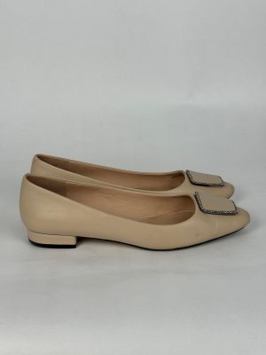 un gros plan sur une paire de chaussures beiges posées sur une surface blanche