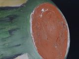 a green and orange vase with a red dot on it