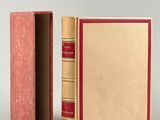 an open book with a red cover sitting on top of a white surface