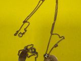 deux colliers en argent posés sur un tissu jaune