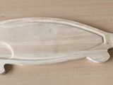 une planche à découper en forme de poisson sur laquelle est posé un couteau