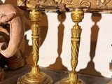 trois bougies dorées posées sur une cheminée, avec un miroir en arrière-plan