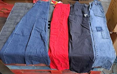 trois paires de jeans posées sur une palette