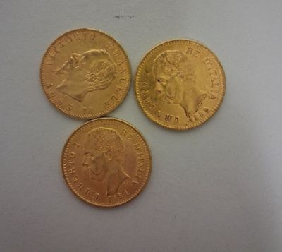trois pièces d'or posées l'une à côté de l'autre sur une surface blanche