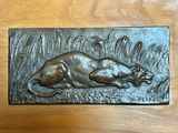 a metal plaque of a dog laying in the grass
