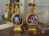 two gold vases with pictures on them sitting on a table