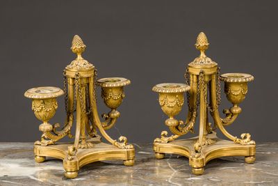 pair of antique brass candlesticks on marble table against grey background