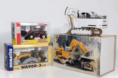 two boxes of toy construction vehicles on a white surface