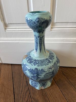 un vase bleu et blanc posé sur un plancher en bois