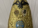 a person holding up a gold helmet with a bird on it