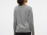 a woman in a grey sweater and black pants stands facing away from the camera
