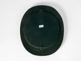 a green hat hanging on a white wall