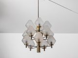 un grand lustre en laiton, dont les abat-jours en verre dépoli sont suspendus au plafond