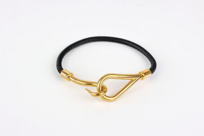 a black leather bracelet with gold plated clasp on a white background