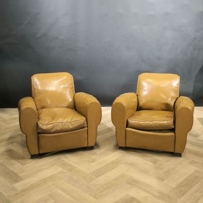 deux fauteuils en cuir marron posés sur un parquet en bois massif