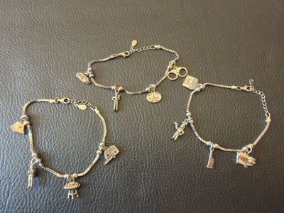 three bracelets with charms and charms on them sitting on a table