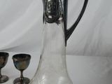 a glass pitcher with a metal handle next to other silverware