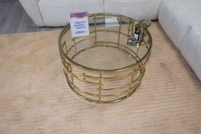 une table basse avec un plateau en verre posée sur un parquet