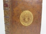 un vieux livre marron orné d'un médaillon doré sur la couverture