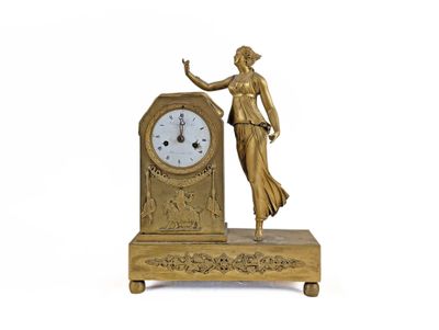 a gold clock with a woman standing next to it