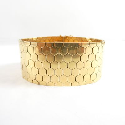 a close up of a gold bracelet on a white surface