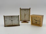 three different sized clocks sitting next to each other on a white surface
