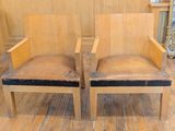 two wooden chairs sitting next to each other on a wooden floor