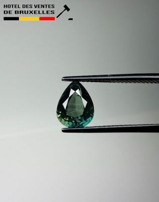 a close up of a green tourmaline gems being held by a pair of pliers