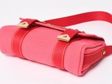 the pink bag has a gold buckle on it and a red strap