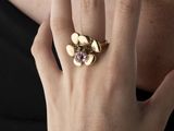 une femme portant à son doigt une bague en or sertie d'une pierre violette