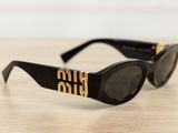 black sunglasses with gold logo on the side of them sitting on a wooden table