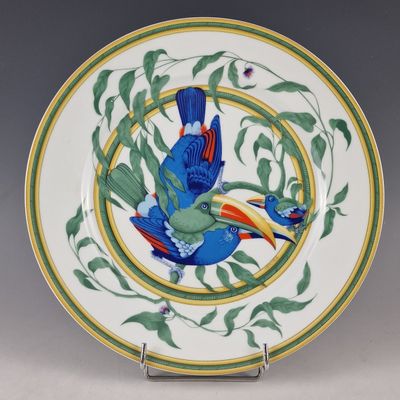 une assiette sur laquelle est peint un oiseau, posée sur un socle